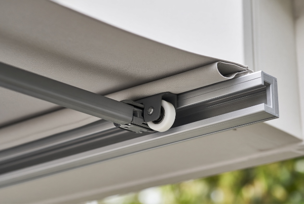 Nylonrollerguidinganoutdoorawningalongitsmetaltrack9-9 Nylon roller guiding an outdoor awning along its metal track